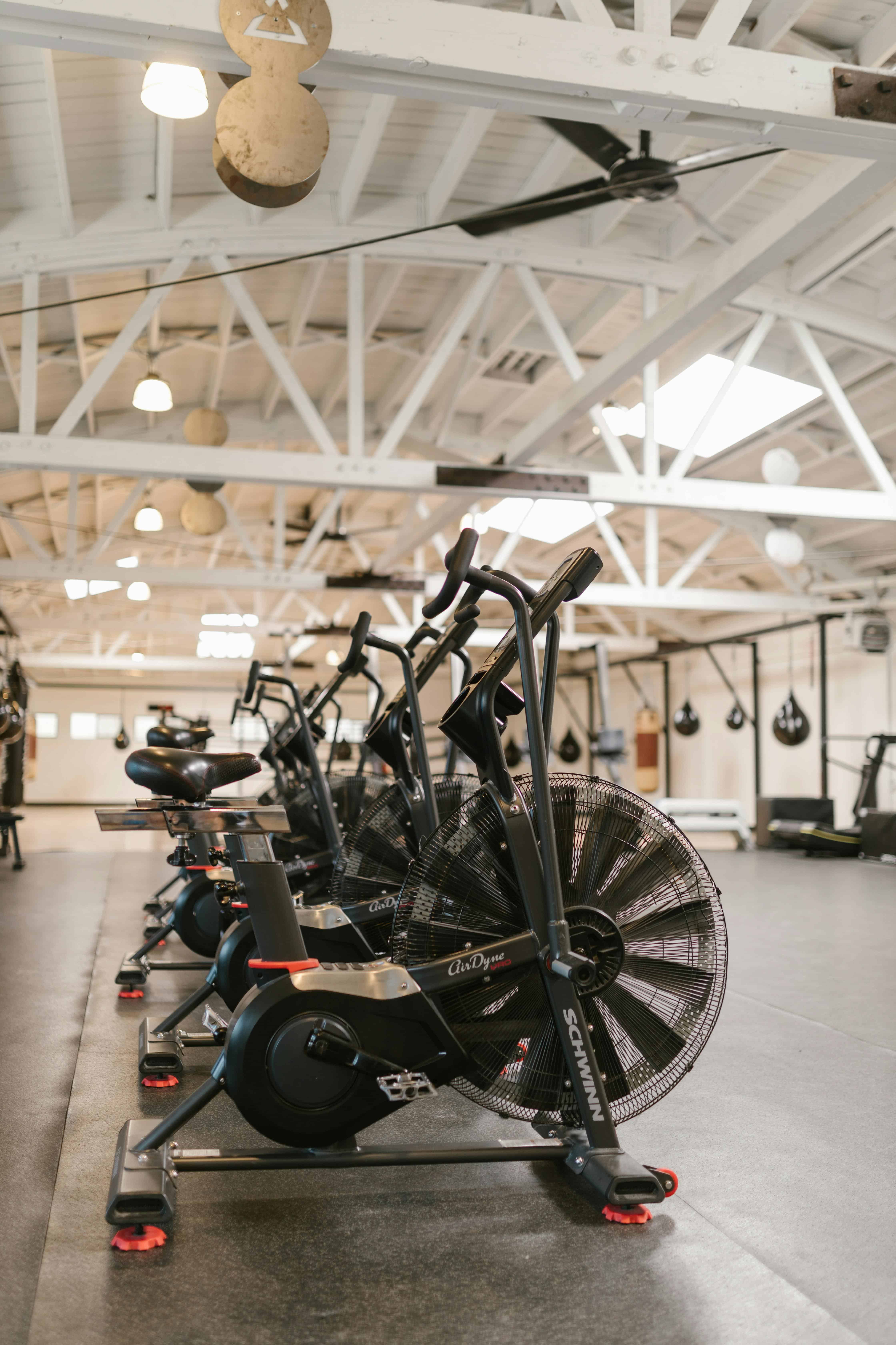 Fileira de bicicletas ergométricas AirDyne com ventiladores circulares em academia moderna